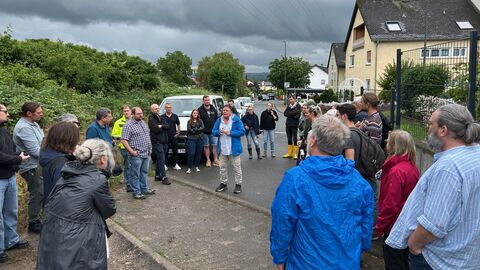 Eine Gruppe von mehreren Personen steht im Kreis zusammen. In ihrer Mitte steht ein Mann, der zu ihnen spricht.