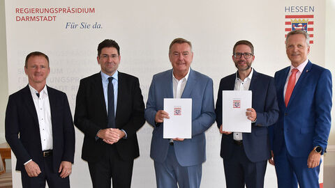 Fünf Personen, zwei davon mit Bescheiden in den Händen