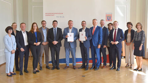 Mehrere Personen im Gruppenbild, zwei davon mit Bescheiden in den Händen