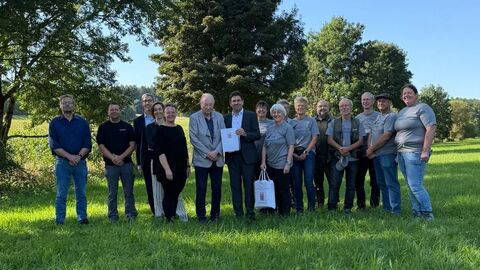 Eine große Gruppe von Menschen steht auf einer Wiese für ein Gruppenfoto bereit.