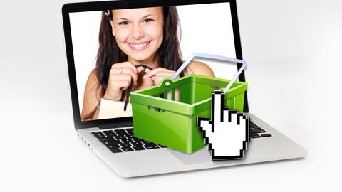 Symbolbild zum Online-Shopping Frauenbild auf PC-Bildschirm mit Einkaufskorb davor