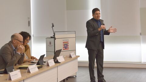 Regionalkonferenz im RP Ein Mann hält ein Mikrofon und spricht hinein.