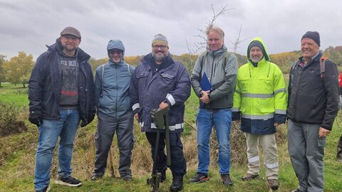 Sechs Männer stehen auf freiem Feld nebeneinander