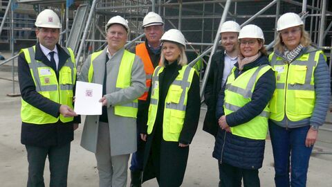 Sieben Personen mit Schutzhelmen auf Baustelle